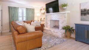 A living room with a brown leather sofa, a fireplace, and a television mounted above it. - 5 Kings, 2 Q pullouts, 5 bedroom, 4 bath, Firepit, Pool, Jacuzi in Knoxville (Knoxville)