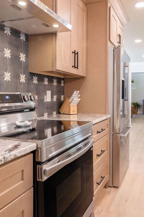 A modern kitchen with stainless steel appliances, wooden cabinets, and a patterned backsplash. - 5 Kings, 2 Q pullouts, 5 bedroom, 4 bath, Firepit, Pool, Jacuzi in Knoxville (Knoxville)
