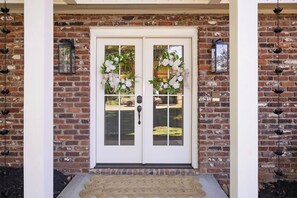 A double door with a brick wall, two flower wreaths, and a doormat. - 5 Kings, 2 Q pullouts, 5 bedroom, 4 bath, Firepit, Pool, Jacuzi in Knoxville (Knoxville)