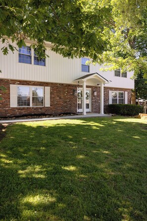 A building with a brick facade, a covered entrance, and a well-maintained lawn. - 5 Kings, 2 Q pullouts, 5 bedroom, 4 bath, Firepit, Pool, Jacuzi in Knoxville (Knoxville)