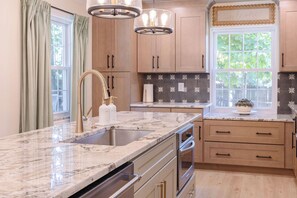 Eine Küche mit Granit Arbeitsplatte, Edelstahlgeräten und Holzschränken.
