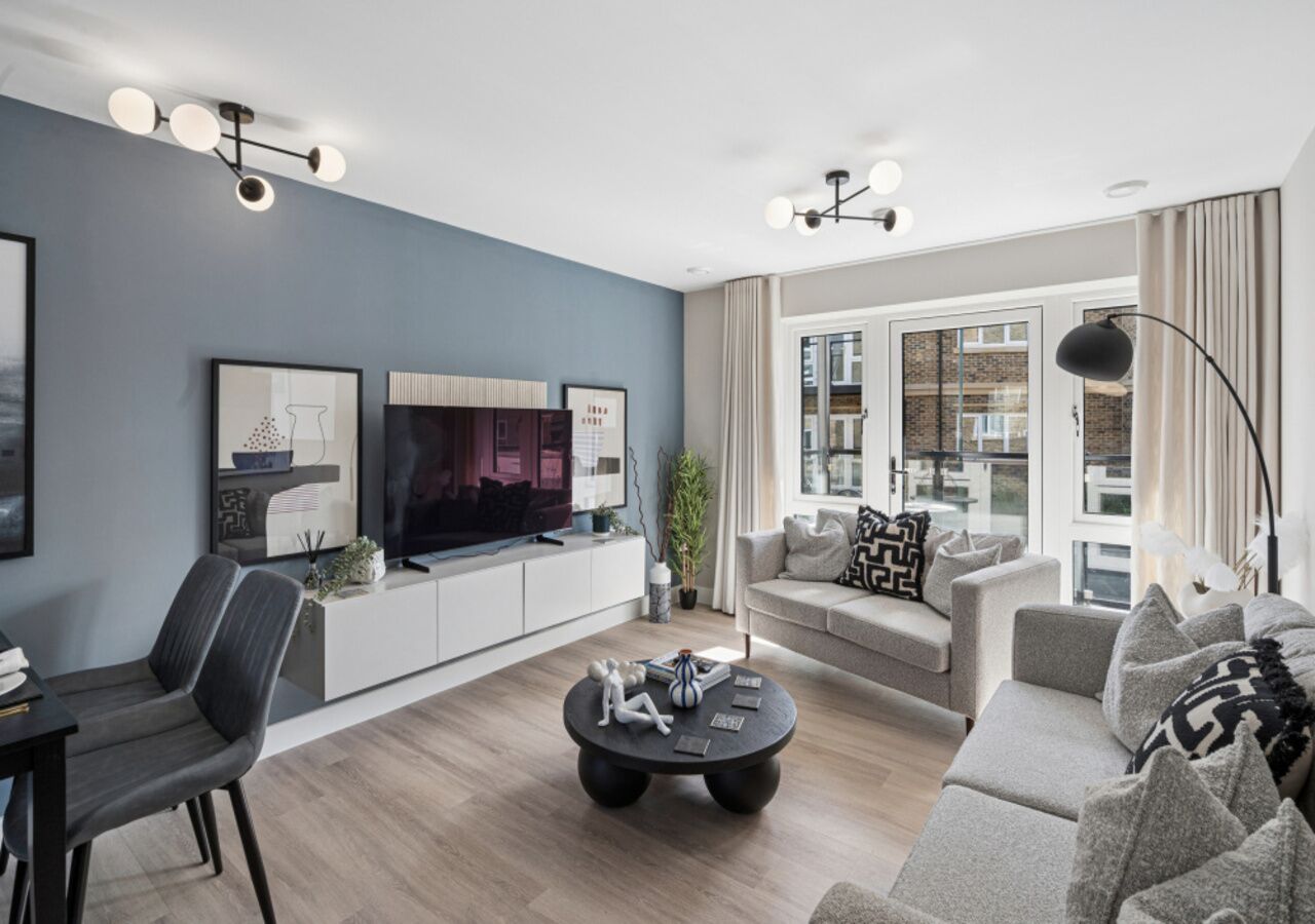Ein modernes Wohnzimmer mit Fernseher, rundem Couchtisch und Sofa.