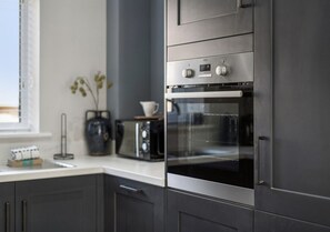 A modern kitchen with dark cabinetry, a built-in oven, and a toaster. - Beautiful modern flat, opposite Ascot Racecourse - Pass the Keys (Ascot)