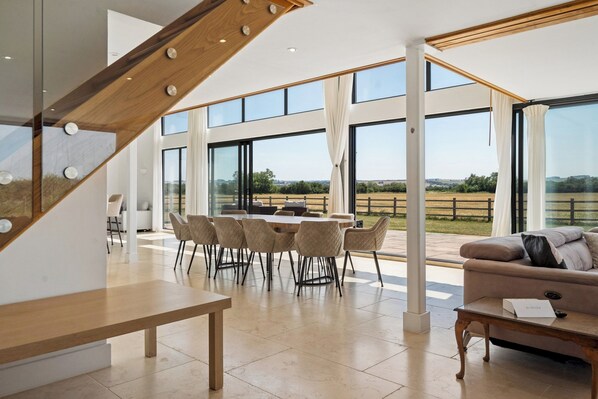 A spacious living area with a dining table and chairs, a sofa, and a wooden bench.
