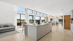 A spacious kitchen with a large island, a dining area with chairs, and a sofa. - Secluded, contemporary barn in expansive gardens - Pass the Keys (Wantage)