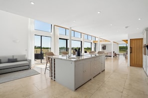A spacious kitchen with a large island, a dining area with chairs, and a sofa. - Secluded, contemporary barn in expansive gardens - Pass the Keys (Wantage)