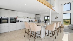 A modern kitchen with a central island, bar stools, and a view of the outdoors. - Secluded, contemporary barn in expansive gardens - Pass the Keys (Wantage)