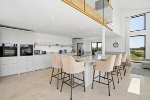 A modern kitchen with a central island, bar stools, and a view of the outdoors. - Secluded, contemporary barn in expansive gardens - Pass the Keys (Wantage)