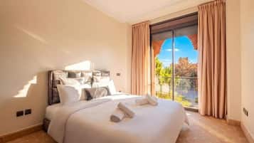 Habitación de hotel con una cama grande, vistas al exterior y un balcón.