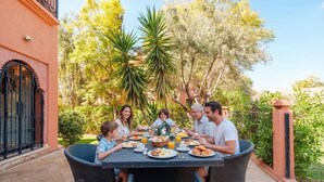 A group of people dining at an outdoor table with a garden view. - 3 BDRM Villa Garden & Pool Front (Marrakech)