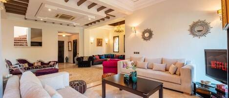 A spacious living room with a large sofa, a coffee table, and a television.