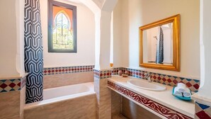 A bathroom with a bathtub, a sink, a mirror, and a window with a decorative door. - 3 BDRM Villa Garden & Pool Front (Marrakech)