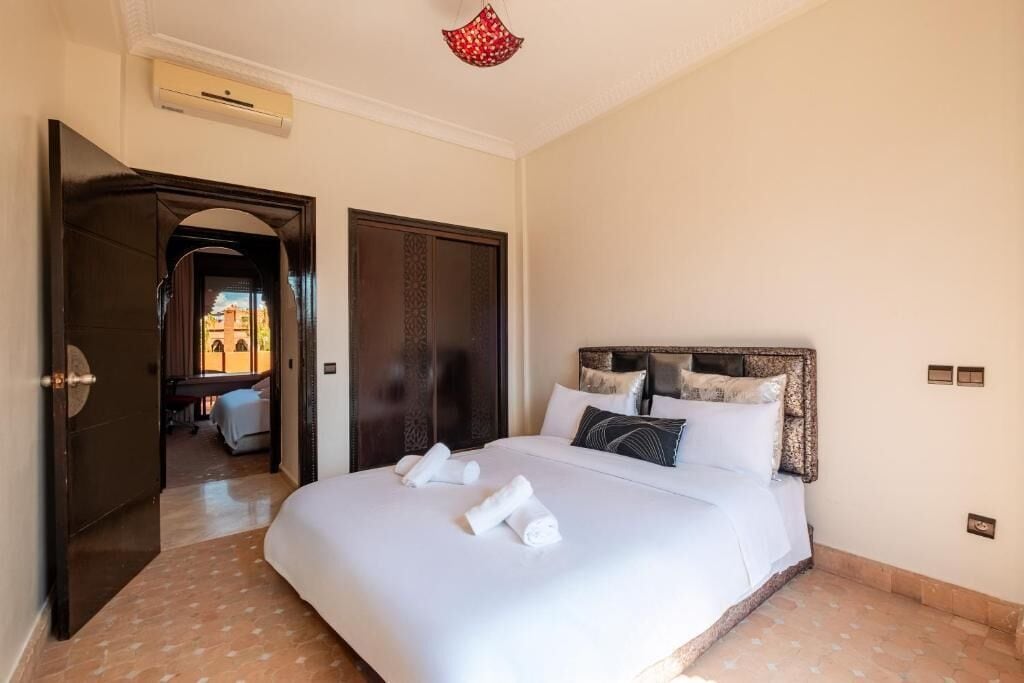 Ein Hotelzimmer mit einem großen Bett, einem Holz-Kopfteil und Blick durch eine offene Tür.