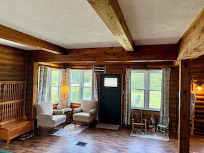 A log cabin interior with a wooden bench, two armchairs, a small table, and a bookshelf. - Your Lake Escape Starts at Balti Bay Lodge New Baltimore 3 bedroom, Boat Parking (New Baltimore)