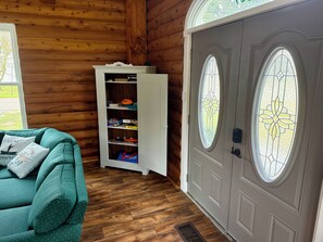 A wooden interior with a teal sofa, a white cabinet with sports equipment, and a door with stained glass windows. - Your Lake Escape Starts at Balti Bay Lodge New Baltimore 3 bedroom, Boat Parking (New Baltimore)
