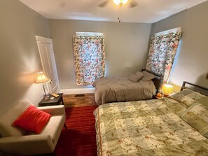 A bedroom with two beds, a red carpet, a white chair, and a nightstand with a lamp. - Your Lake Escape Starts at Balti Bay Lodge New Baltimore 3 bedroom, Boat Parking (New Baltimore)