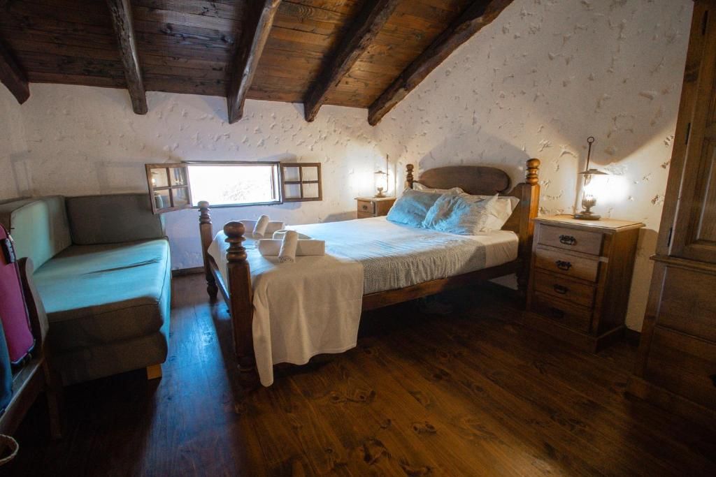 A bedroom with a wooden bed, a bedside table, a nightstand, a chair, and a window.