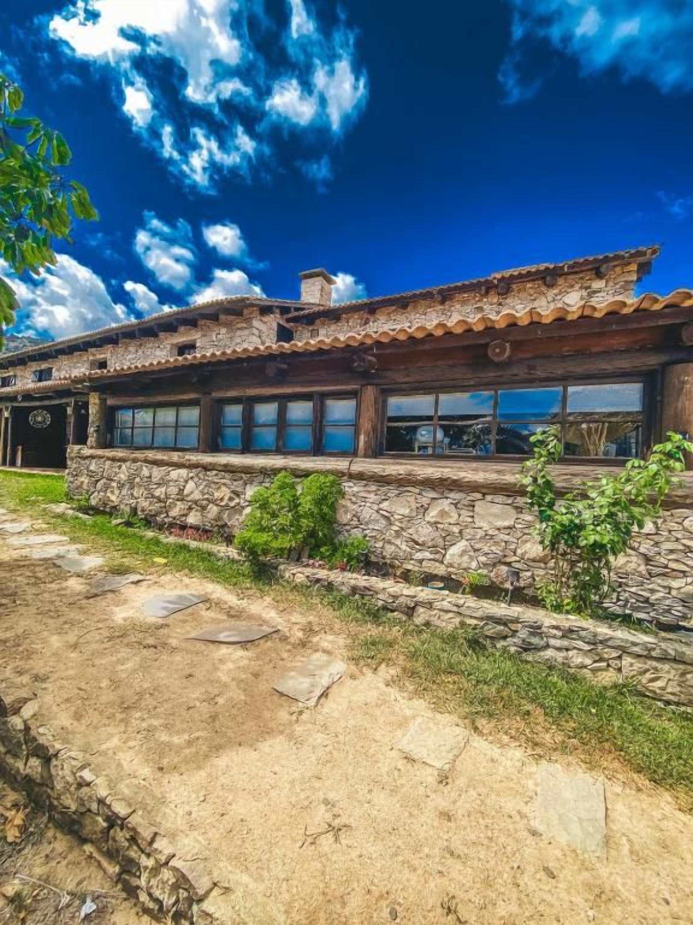 A rustic building with a stone facade, large windows, and a wooden roof.