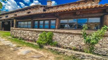 A rustic building with a stone facade, large windows, and a wooden roof.