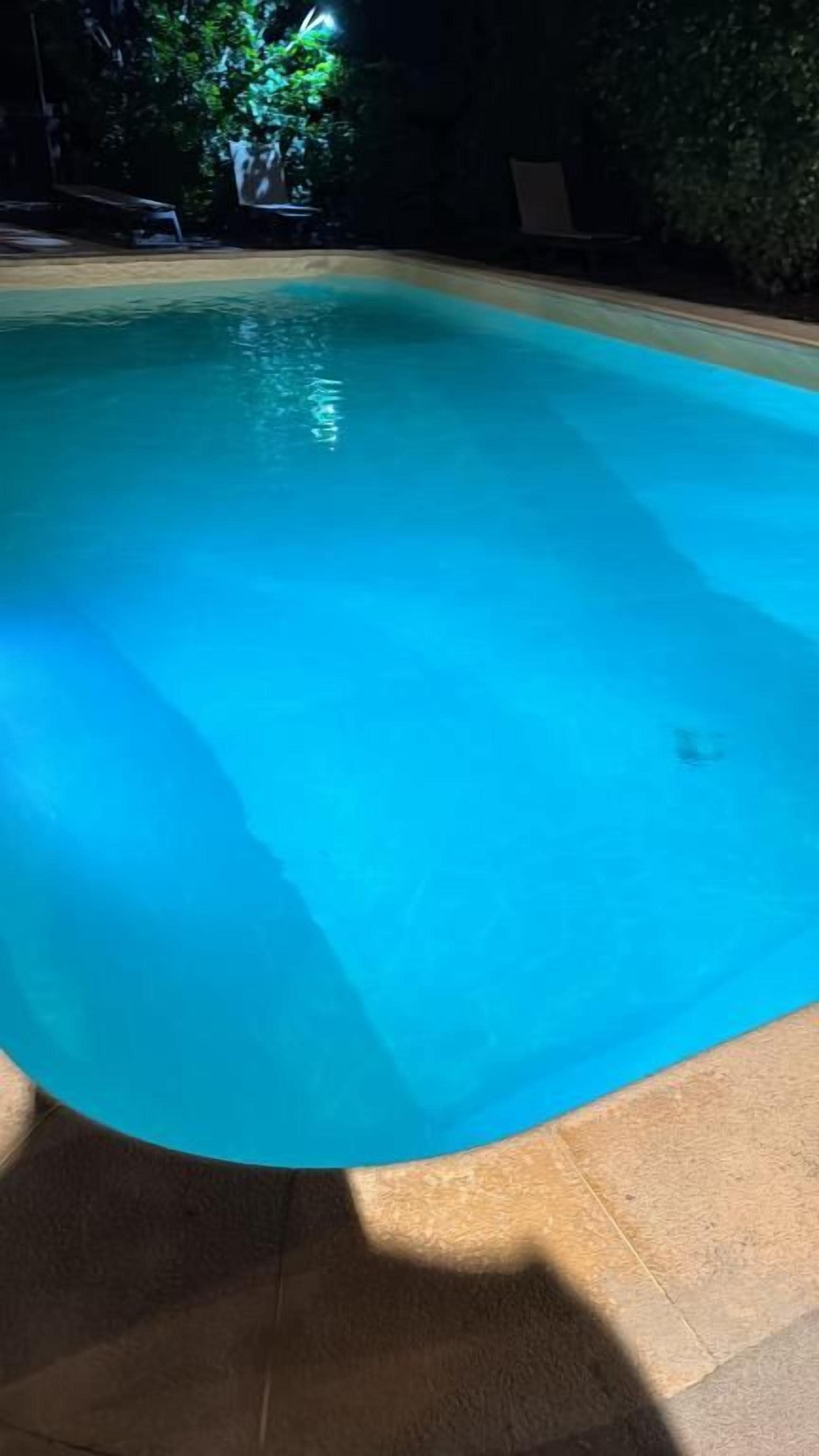 A swimming pool with a curved edge, surrounded by a tiled deck.