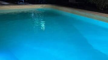 A swimming pool with a curved edge, surrounded by a tiled deck.