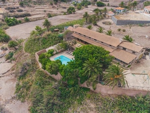 Ein großes Haus mit Swimmingpool, umgeben von üppiger Vegetation und Palmen.