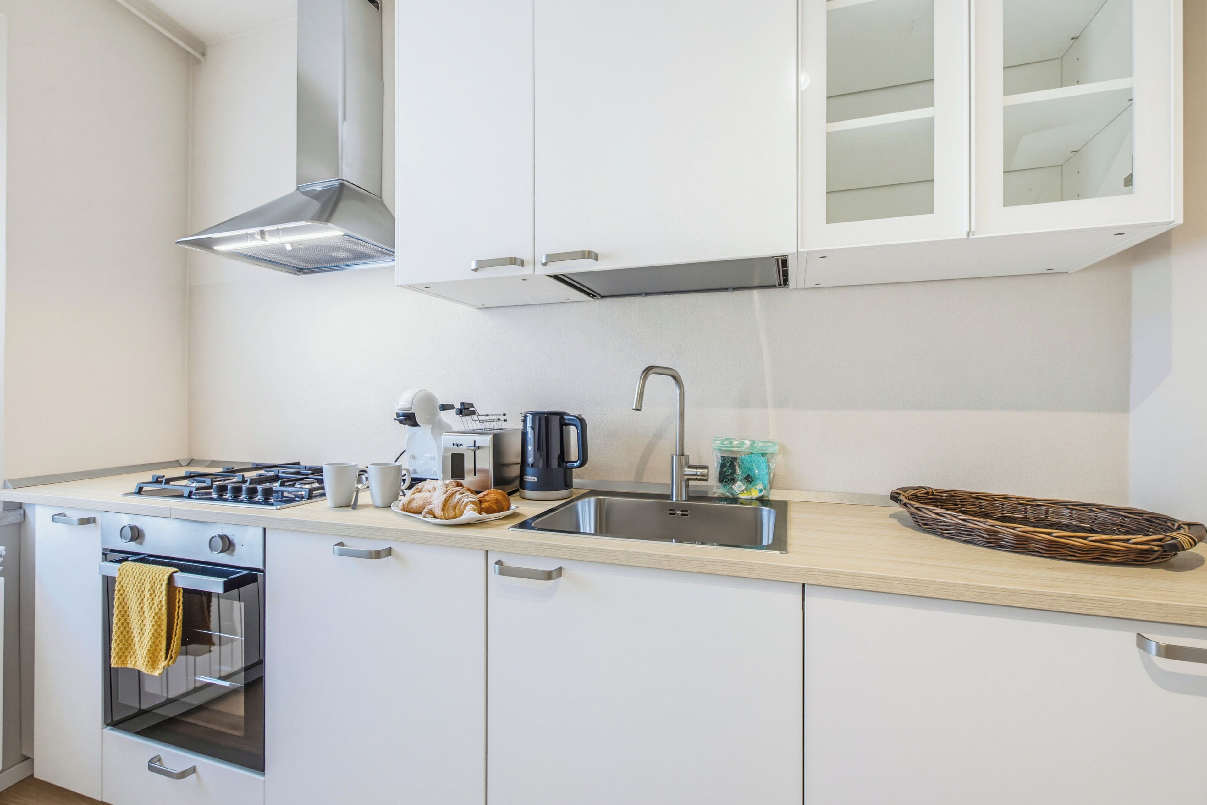 Una cocina moderna con armarios blancos, electrodomésticos de acero inoxidable y encimera de madera.