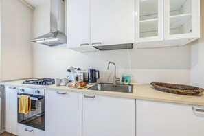 A modern kitchen with white cabinets, stainless steel appliances, and a wooden countertop. - Clara's Olivi (Lavaiano)