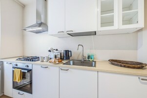 Una cucina moderna con mobili bianchi, elettrodomestici in acciaio inossidabile e un piano di lavoro in legno.