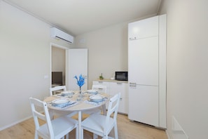 A compact kitchen with white cabinets, a microwave, and a dining area with a table set for two.