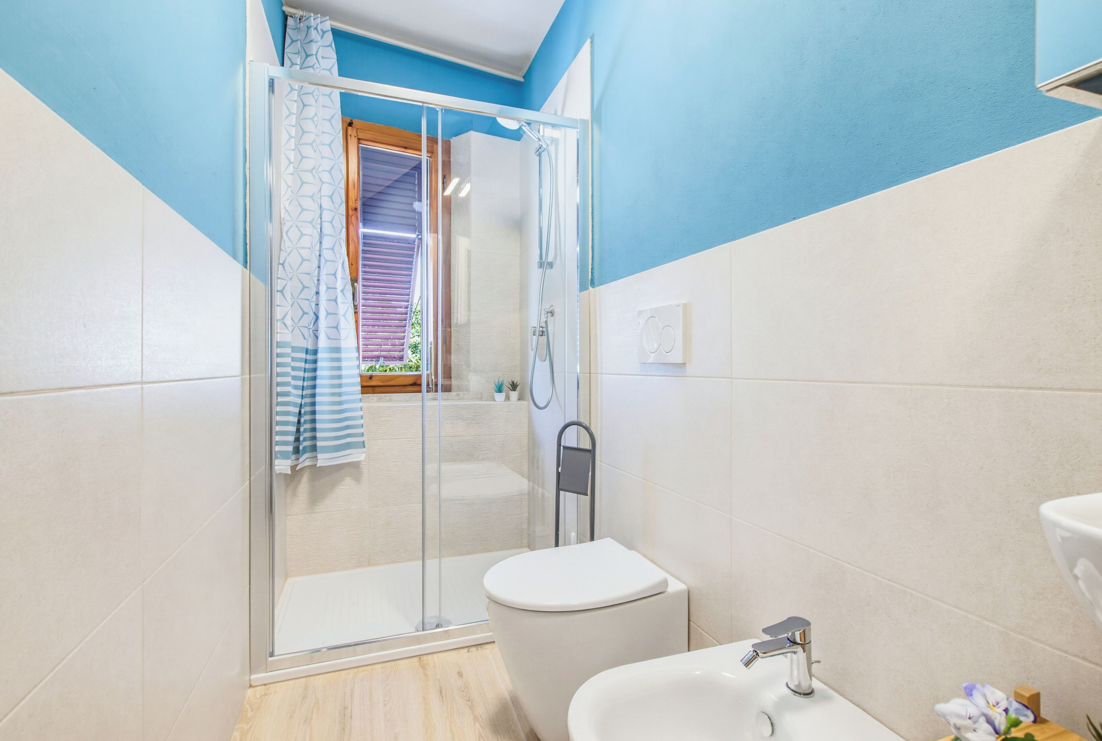 Un baño con cabina de ducha de vidrio, inodoro y lavamanos.