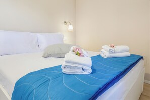 Ein Hotelzimmer mit einem Bett, Kissen, einer blauen Tagesdecke und zwei gefalteten Handtüchern mit Blumenmuster.
