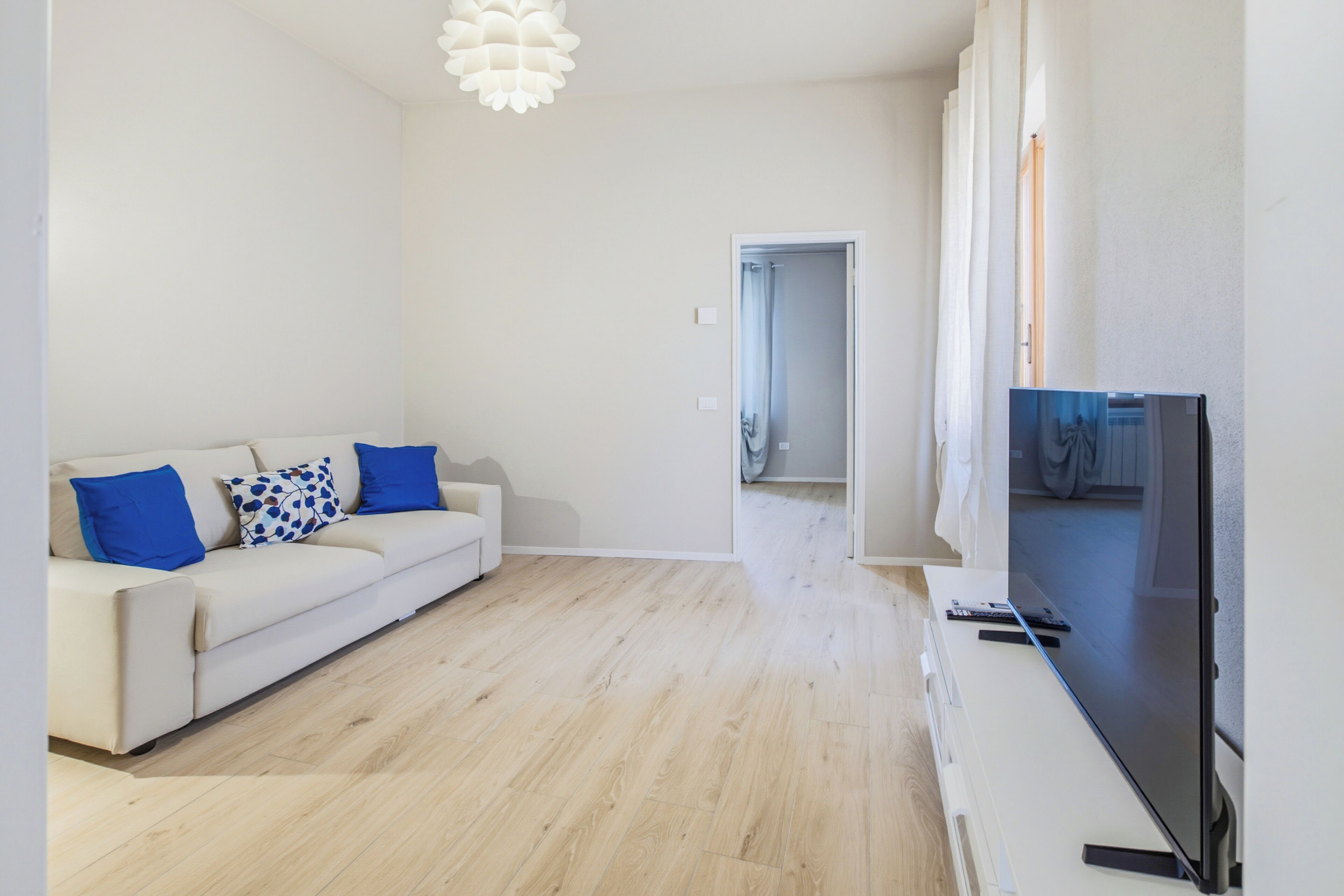 Una sala de estar moderna con un sofá, un televisor de pantalla plana y piso de madera.