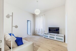 Una sala moderna con un sofá, un mueble para televisión y una puerta que da a otra habitación.