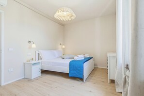 A bedroom with a bed, bedside tables, a hanging light fixture, and a window with curtains. - Clara's Olivi (Lavaiano)