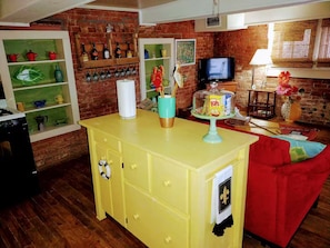 A living room with a brick wall, a yellow cabinet, a red couch, a television, and various decorative items.