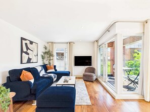 Ein modernes Wohnzimmer mit einer Couch, einem Hocker und einem Flachbildfernseher.