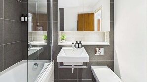 A modern bathroom with a glass shower enclosure, a white sink, and a separate toilet area. - Large, Bright Westminster Apartment with Balcony (Greater London)
