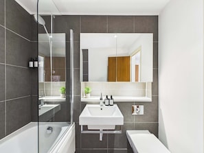 A modern bathroom with a glass shower enclosure, a white sink, and a separate toilet area. - Large, Bright Westminster Apartment with Balcony (Greater London)