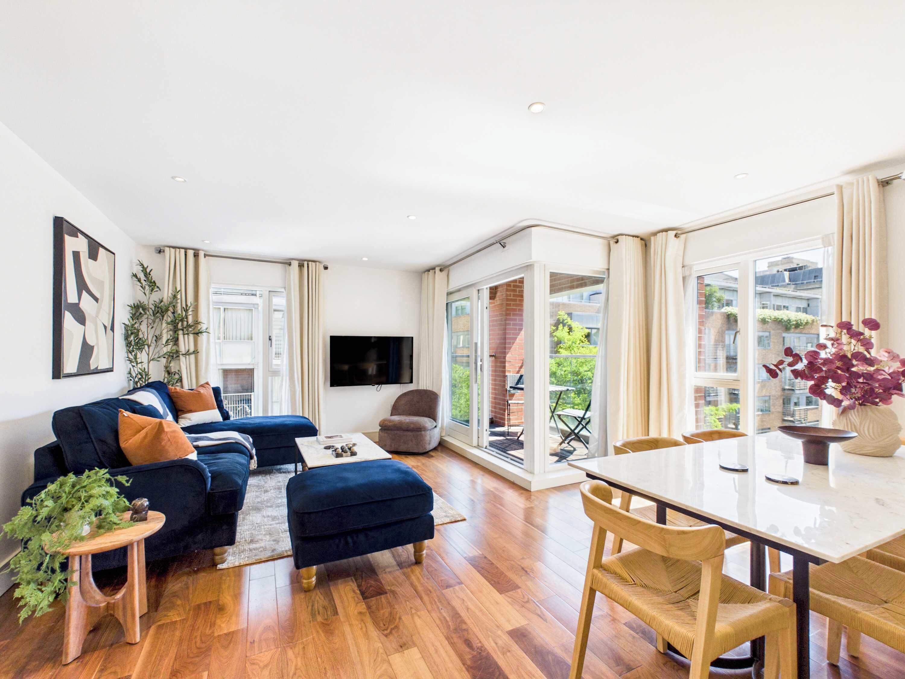A modern living room with a sofa, ottoman, and a dining table with chairs.