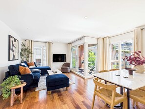 Una sala de estar moderna con un sofá, un reposapiés y una mesa de comedor con sillas.
