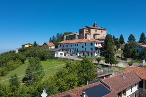 A hillside residential area with terraced houses, a prominent church with a bell tower, and lush greenery. - A renovated farmhouse in the heart of the Langhe, 7 km from Alba. (Piemonte)
