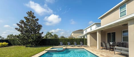 A rectangular swimming pool with a tiled edge, surrounded by a brick patio.