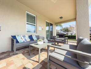 An outdoor patio with a gray sofa, a white table, and a grill. - UFC Champion José Aldo’s 8-BR Near to Disney (Kissimmee)