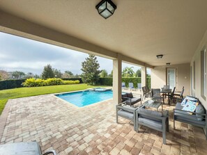 A covered outdoor area with a swimming pool, patio furniture, and a view of the surrounding landscape. - UFC Champion José Aldo’s 8-BR Near to Disney (Kissimmee)
