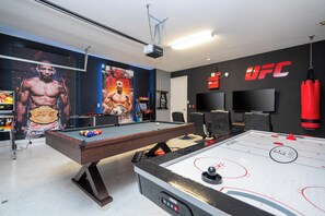 A recreational room with a pool table, a foosball table, and a wall-mounted TV. - UFC Champion José Aldo’s 8-BR Near to Disney (Kissimmee)