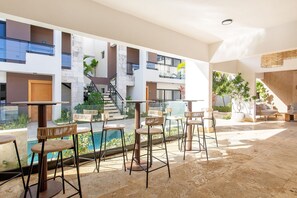 Un espace extérieur moderne aménagé avec des sièges et une piscine, entouré d’un immeuble à plusieurs niveaux doté de balcons.