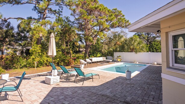 A backyard with a swimming pool, lounge chairs, and a covered patio area. - Gulfport Getaway - Beach, Downtown, Shops nearby (South Pasadena)