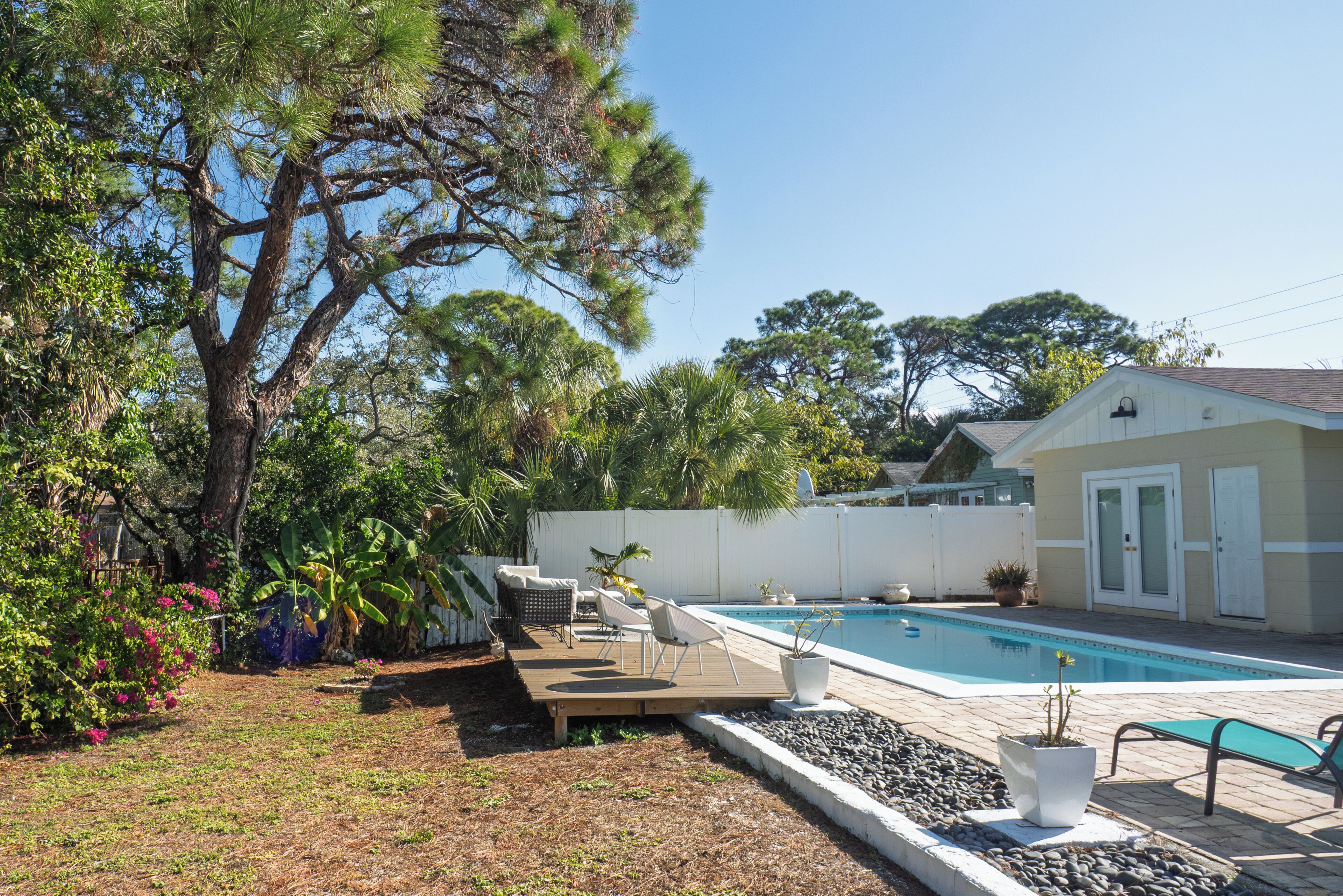 A backyard with a swimming pool, outdoor furniture, and a variety of plants.