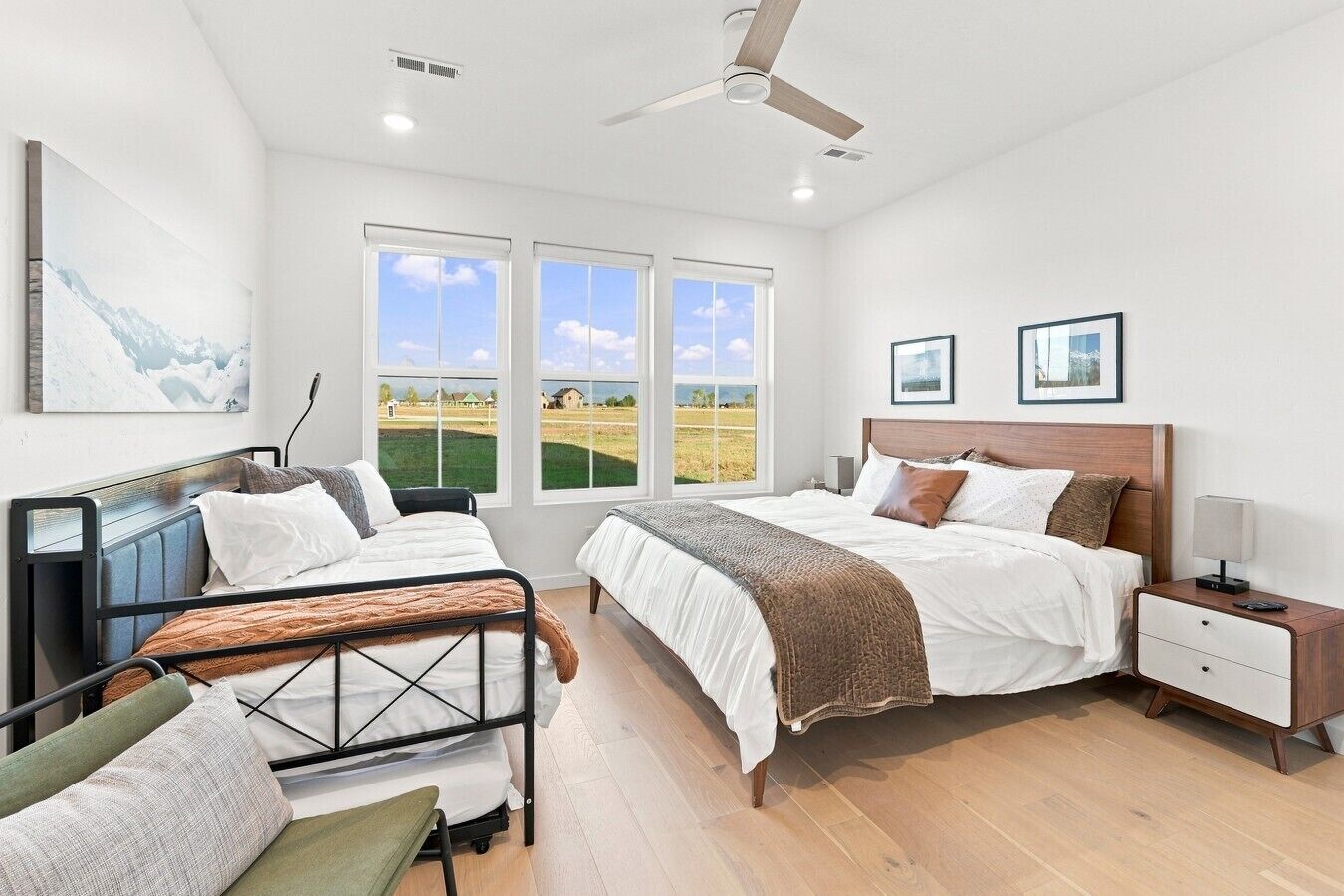 A bedroom with two beds, a desk, a chair, and a ceiling fan.